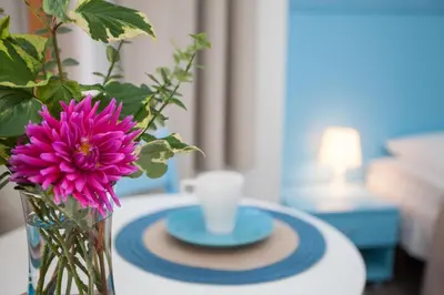 a vase with a pink flower and a cup on a table at Moja Accommodation in Kaunas