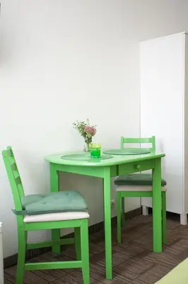 a green table and chair with a vase of flowers on it at Moja Accommodation in Kaunas