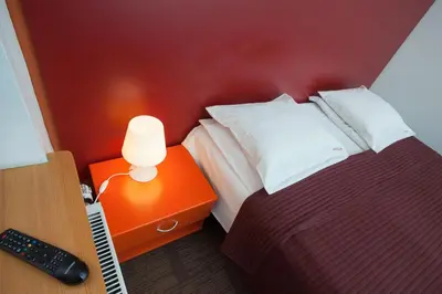 a bedroom with a bed and a desk with a remote control at Moja Accommodation in Kaunas