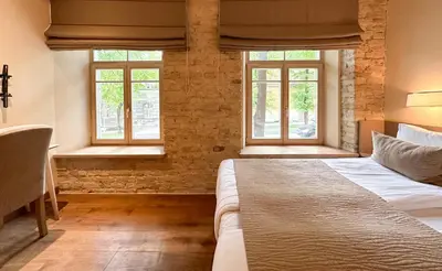 a bedroom with a bed and two windows at New Town Home 2 in Vilnius
