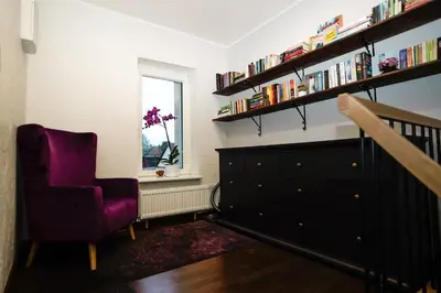 a living room with a purple chair and a dresser at Garden Cottage in Šiauliai