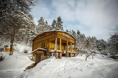 a wooden house in the snow with snow covered trees at Pasakų namelis dviems su vaizdu į ežerą in Esperanza