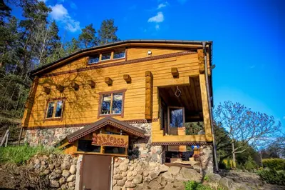 a wooden house on top of a stone building at Pasakų namelis dviems su vaizdu į ežerą in Esperanza
