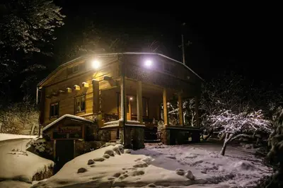 a house in the snow at night with lights at Pasakų namelis dviems su vaizdu į ežerą in Esperanza