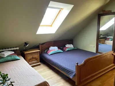 a attic bedroom with two beds and a mirror at Gallery Guest Rooms in Kernavė