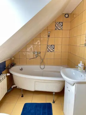 a bathroom with a white tub and a sink at Gallery Guest Rooms in Kernavė