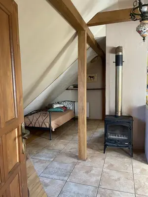 a room with a stove and a bed in a attic at Gallery Guest Rooms in Kernavė