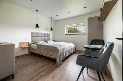 a bedroom with a bed and a chair at Vila Valentino in Klepšiai