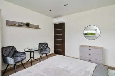a bedroom with a bed and two chairs and a table at Vila Valentino in Klepšiai