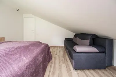 a bedroom with a bed and a couch in a attic at Vila Valentino in Klepšiai