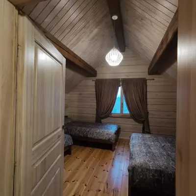 an attic room with two beds and a window at Užmiesčio trobelė in Mackėnai