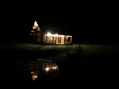 a house lit up at night with lights on it at Užmiesčio trobelė in Mackėnai