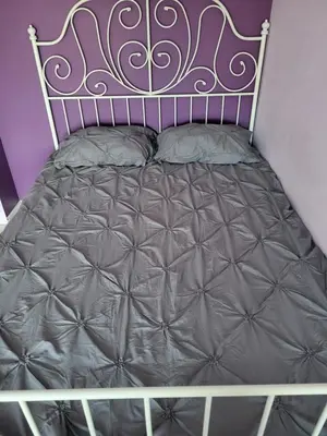 a bed in a purple room with a metal bed frame at four room's apartments in Vilnius