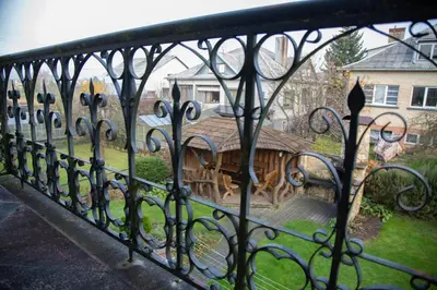 a iron fence with a wooden house behind it at Azimut Guest House Quiet Getaway Garden Sauna in Šiauliai