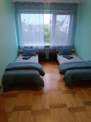 two beds in a room with two windows at Azimut Guest House Quiet Getaway Garden Sauna in Šiauliai