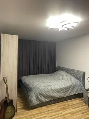 a bedroom with a bed and a guitar in it at Jaukus butas Jonavoje in Jonava