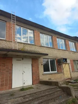 a brick house with white doors and a ladder at 2 kambarių butas 100 m nuo paplūdimio in Gudeliai