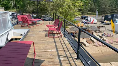a wooden deck with red chairs and a playground at Aquaspot Kaunas in Kaunas