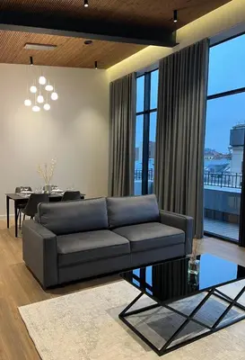 a living room with a black couch and a table at Maironio apartamentai in Kaunas