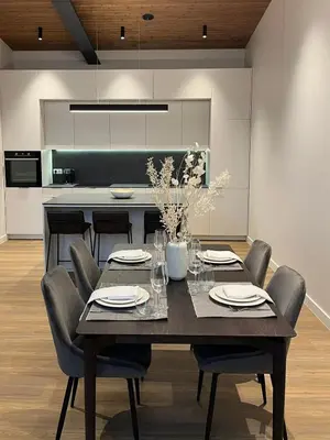 a dining room with a table with chairs and a kitchen at Maironio apartamentai in Kaunas