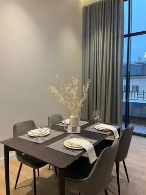 a dining room table with chairs and a black table and a window at Maironio apartamentai in Kaunas