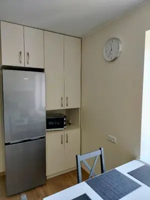 a kitchen with a refrigerator and a clock on the wall at Apartamentai dviems Ignalinoje in Ignalina