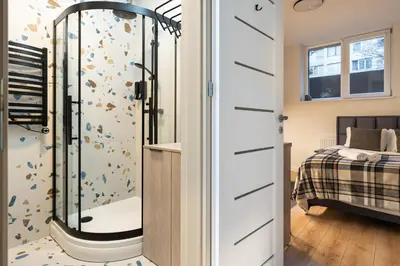 a bathroom with a shower next to a bed at Studio Chic in Vilnius