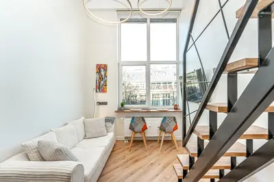 a living room with a white couch and a large window at Cozy loft in city center in Vilnius