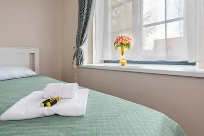 a bed with towels and a vase with flowers in a window at Shanti barracks apartment #2 by Polo Apartments in Kaunas