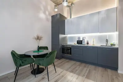 a kitchen with a table and green chairs at Shanti barracks apartment #2 by Polo Apartments in Kaunas