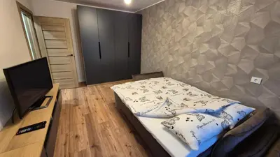 a small bedroom with a bed and a television at Savannah Ateities Apartamentai in Panevėžys