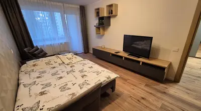 a bedroom with a bed and a flat screen tv at Savannah Ateities Apartamentai in Panevėžys