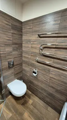 a bathroom with a toilet and a wooden wall at Savannah Ateities Apartamentai in Panevėžys