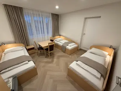 a hotel room with three beds and a table and a dining room at Žilina in Marijampolė