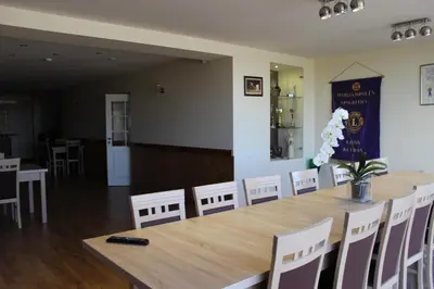 a dining room with a large wooden table and white chairs at Žilina in Marijampolė