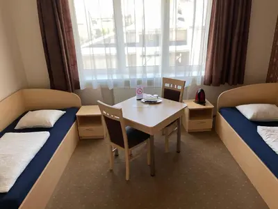 a room with two beds and a table and chairs at Žilina in Marijampolė