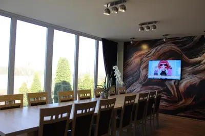 a dining room with a large table and a tv on a wall at Žilina in Marijampolė