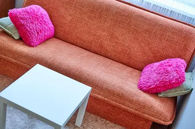 two pink pillows sitting on a couch next to a table at Tokyo Vibes - Private Sleeping Pods Hostel, Self check-in in Vilnius