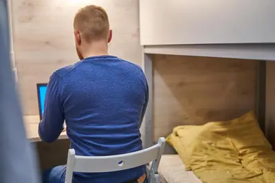 a man sitting in a chair in front of a laptop at Tokyo Vibes - Private Sleeping Pods Hostel, Self check-in in Vilnius