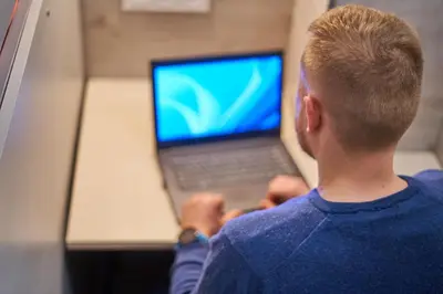 a man sitting in front of a laptop computer at Tokyo Vibes - Private Sleeping Pods Hostel, Self check-in in Vilnius