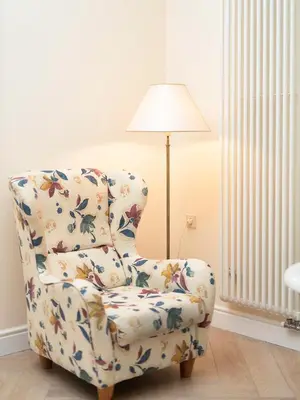 a floral chair with a lamp in a living room at Spacious, Very cosy, Stylish and Perfectly located in Vilnius