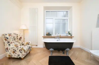 a bathroom with a claw foot tub and a chair at Spacious, Very cosy, Stylish and Perfectly located in Vilnius