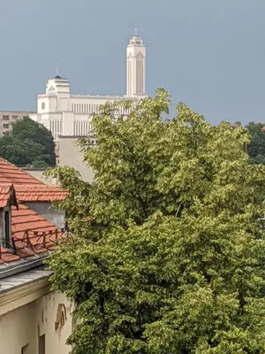 a tree in front of a building with buildings in the background at Mini Studio Apartment in Kaunas