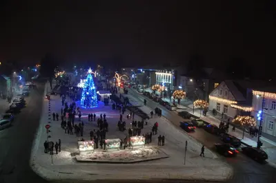 a group of people standing around a christmas tree on a city street at Komfortita in Utena