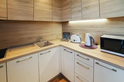 a kitchen with white cabinets and a microwave and a sink at Ballare Druskininkai in Druskininkai