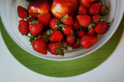 a bowl of strawberries on top of a green plate at Ballare Druskininkai in Druskininkai