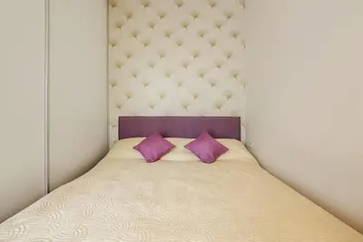 a bed with two purple pillows in a room at Ballare Druskininkai in Druskininkai