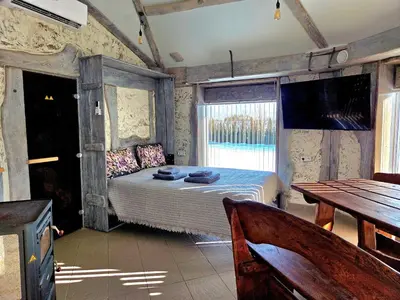 a bedroom with a bed and a table and a television at Egliškių Oazė Sodyba su pirtimi kubilu- privatumas garantuotas in Vilnius