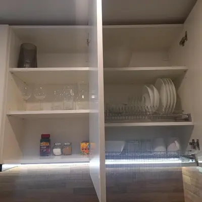a cupboard with plates and bowls and glasses on it at Cozy small apartment #5A in Šiauliai
