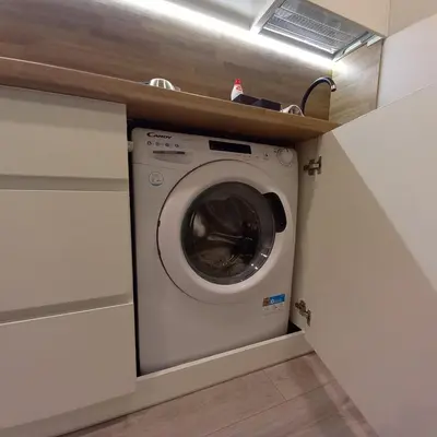 a washing machine in a laundry room with a shelf at Cozy small apartment #5A in Šiauliai